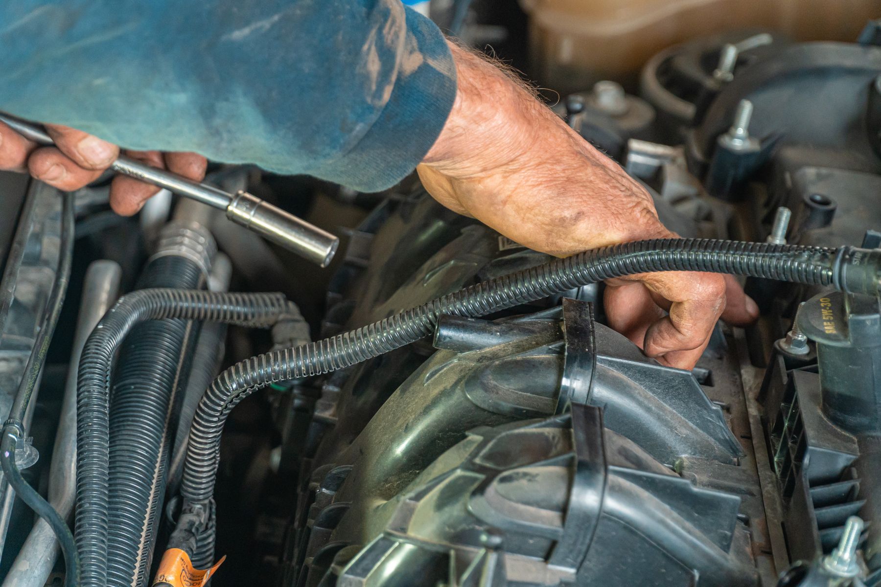 Automotive technician repairing a vehicle engine in a workshop